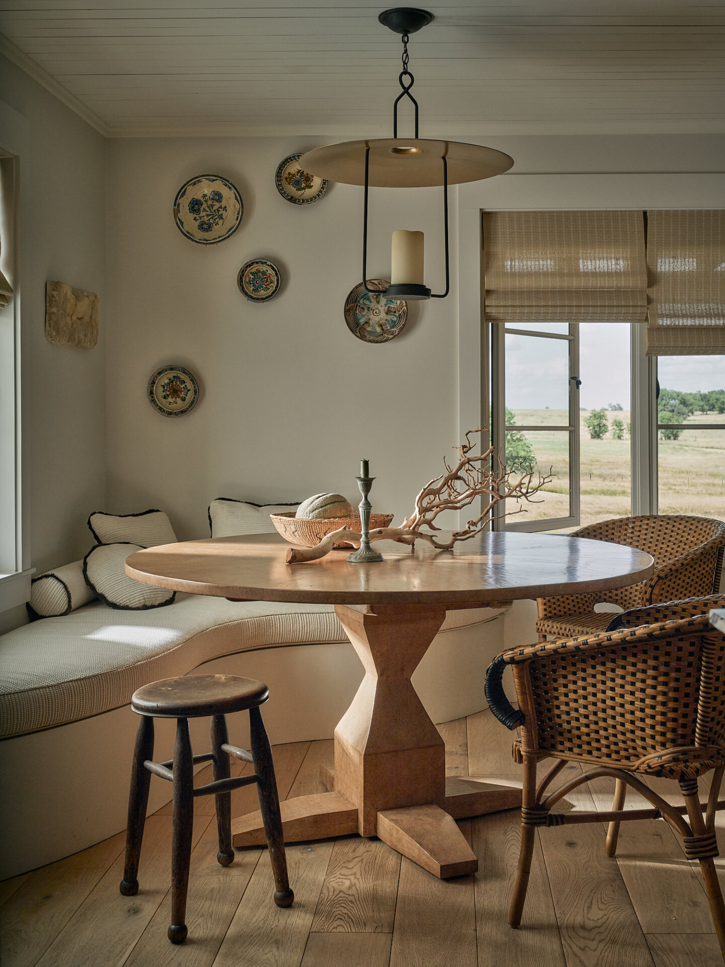Bright dining space with wooden table, rattan chairs, and decorative wall plates.