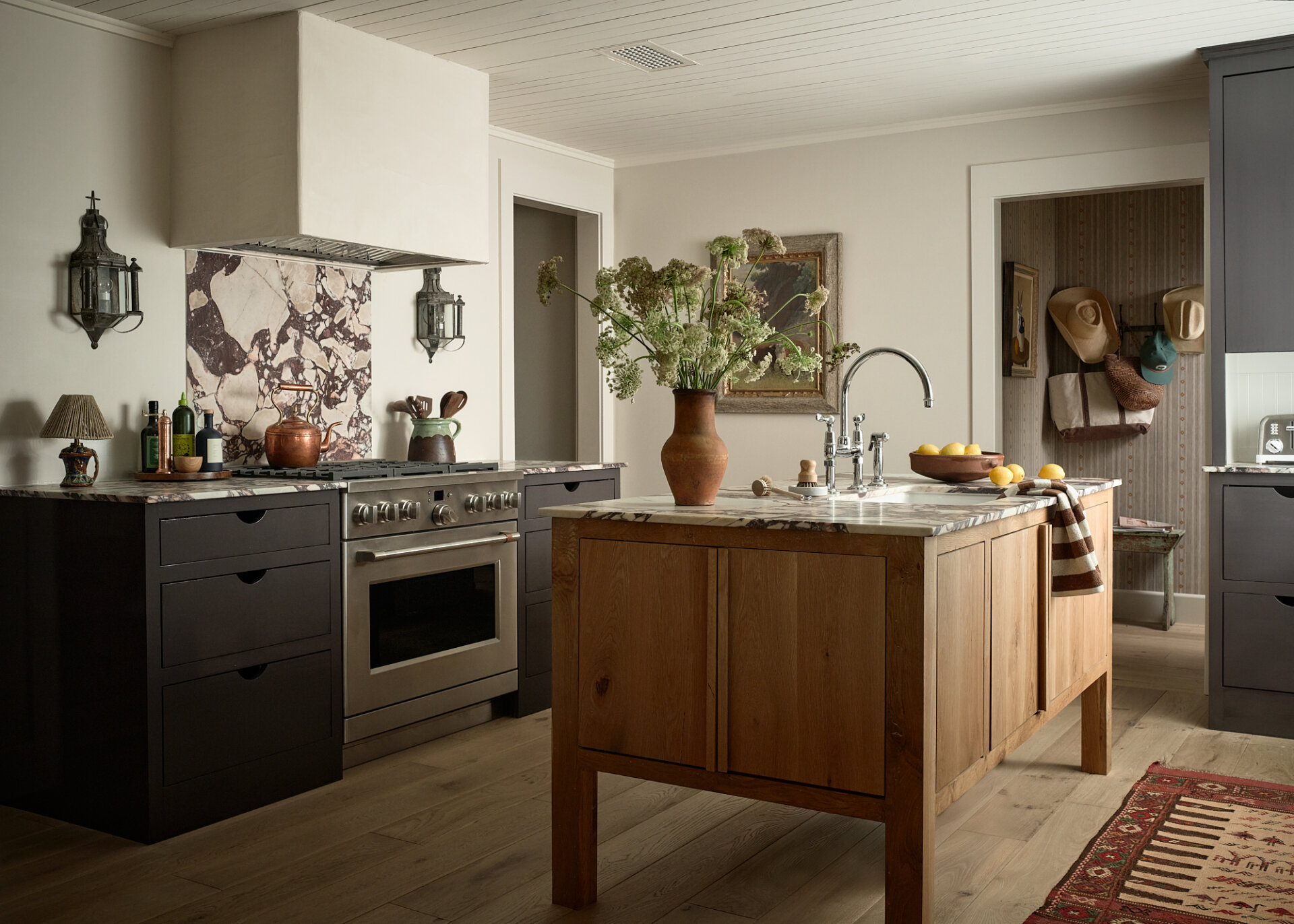 Stylish kitchen with black and wood cabinetry, marble backsplash, and central island.