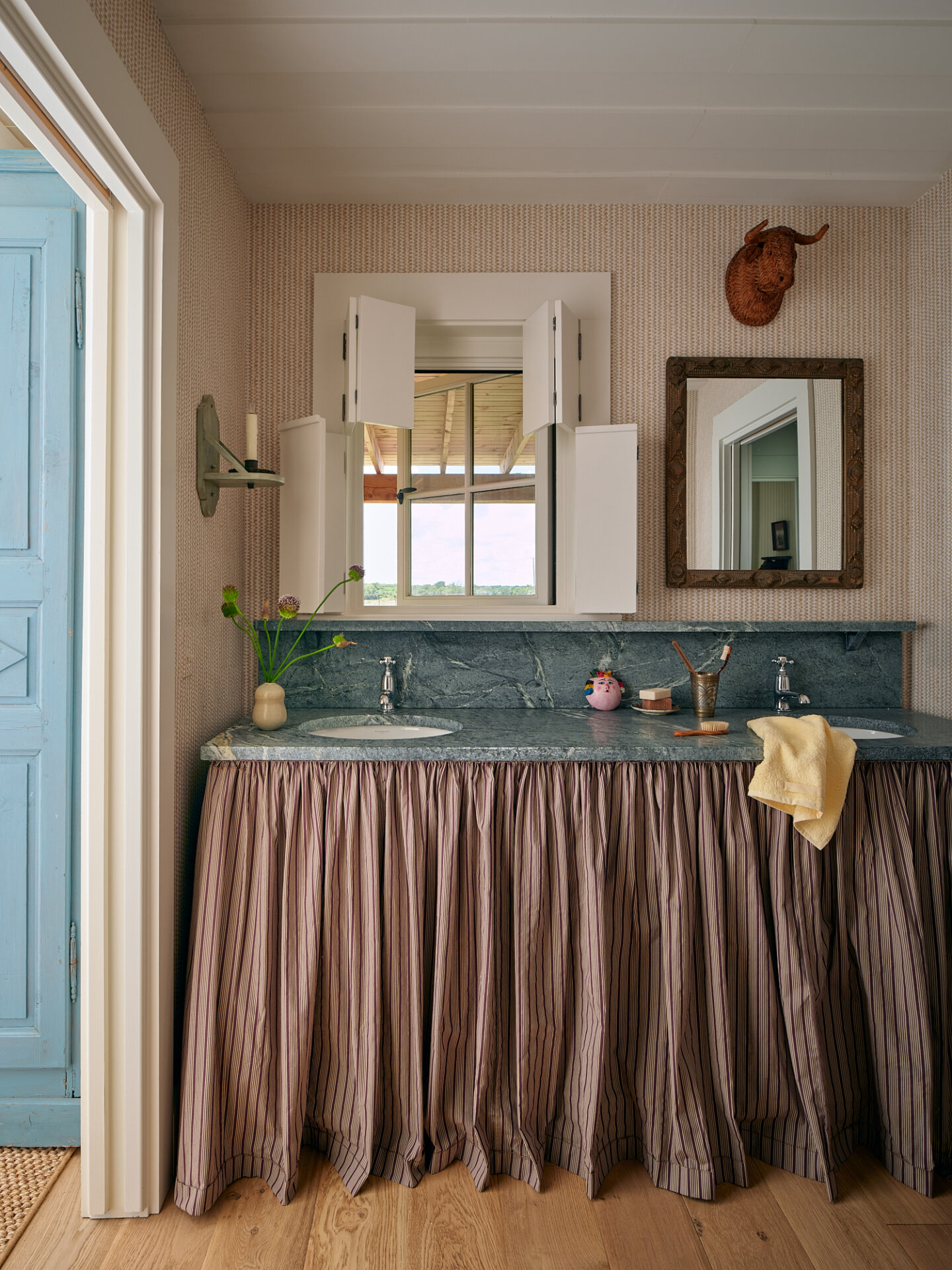 Cozy bathroom with vintage decor, window view, and pink ruffled curtain.